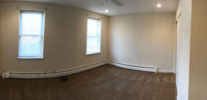 an empty room with white walls and two windows
